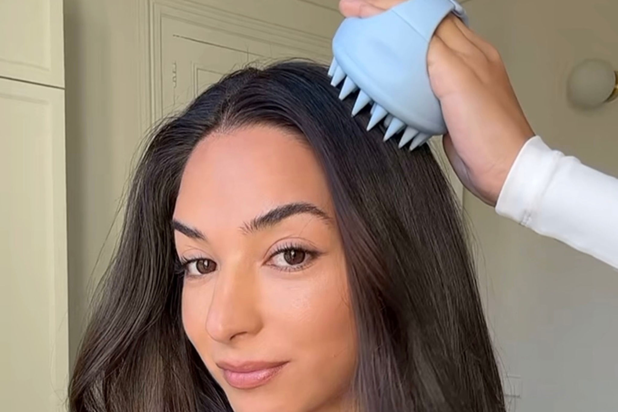Chica utilizando el masajeador de cuero cabelludo.
