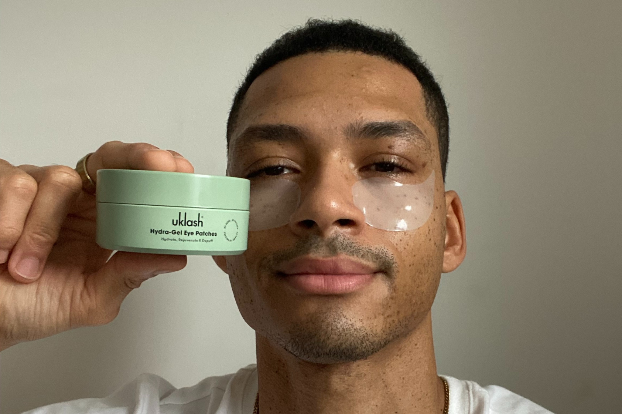 Hombre enseñando sus parches para ojos uklash en un rutina facial.